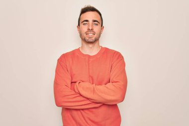 Mavi gözlü, sıradan bir süveter giyen, beyaz arka planda duran, kollarını kavuşturup kameraya gülümseyen genç yakışıklı bir adam. Pozitif kişi.