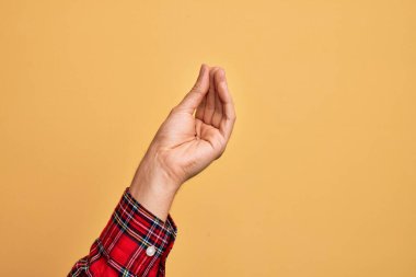 Kafkas genci parmaklarını izole edilmiş sarı arka planda gösteriyor. Parmaklarıyla İtalyan hareketi yapıyor. İletişim hareketi.