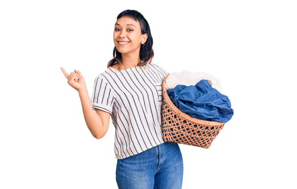 Ung Kvinna Som Håller Tvättkorg Ler Glad Pekar Med Hand — Stockfoto