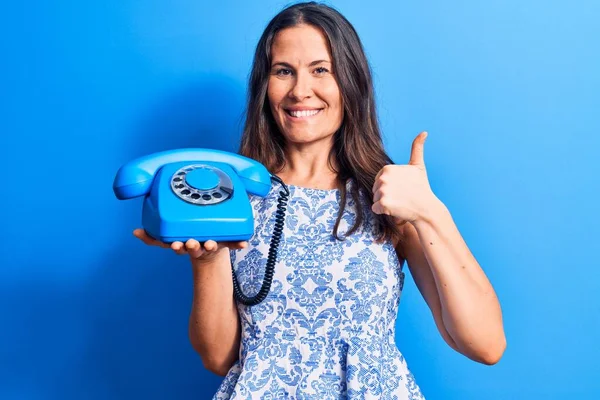 Joven Hermosa Morena Sosteniendo Teléfono Vintage Sobre Fondo Azul Aislado — Foto de Stock