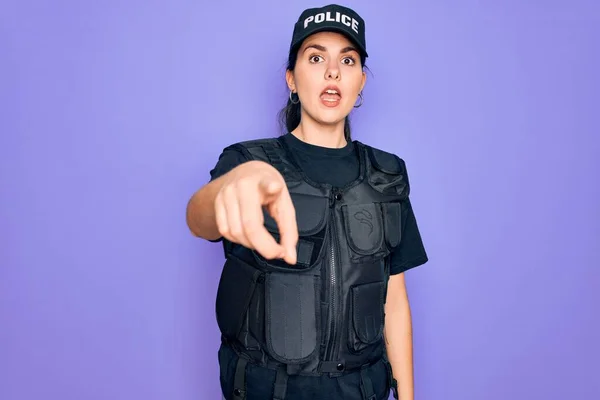 Young police woman wearing security bulletproof vest uniform over purple background pointing displeased and frustrated to the camera, angry and furious with you