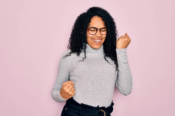 Młoda Afroamerykanka Ubrana Sweter Okulary Różowym Tle Świętująca Sukces Podniesionymi — Zdjęcie stockowe