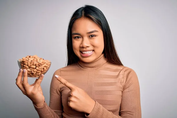 Genç Asyalı Kız Elinde Sağlıklı Fıstıklarla Beslenme Düzenini Bembeyaz Arka — Stok fotoğraf