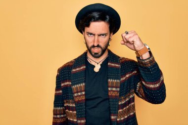 Yakışıklı, İspanyol asıllı bohem bir adam hippi tarzı giyinmiş ve bohem şapkalı kızgın ve kızgın. Öfkeyle bağırırken yumruğunu kaldırıyor. Öfke ve agresif kavram.