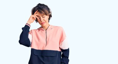 Spor kıyafetleri giyen genç ve güzel bir kadın. Alnındaki bir sorun yüzünden endişeli ve stresli. Kriz için endişeli. 