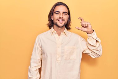 İş kıyafetleri giymiş, gülümseyen, kendine güvenen, el hareketleriyle hareket eden, parmaklarıyla işaret eden ve kameraya bakan genç yakışıklı bir adam. ölçüm kavramı. 