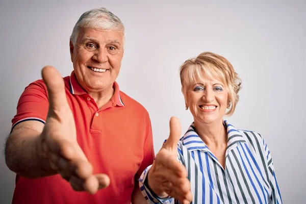 一对年迈的年轻夫妇站在孤独的白色背景上 友好地微笑着 握手致意和欢迎 成功的业务 — 图库照片