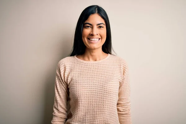 顔に幸せとクールな笑顔で孤立した背景にエレガントなピンクのセーターを着て若い美しいヒスパニック系の女性 運のいい人 — ストック写真