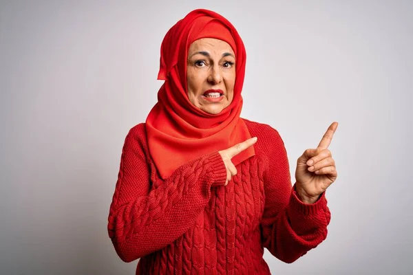 中世のブルネット女性身に着けていますムスリム伝統的なヒジャーブ上の隔離された白い背景脇に心配し 両方の手で神経を尖らせます 懸念と驚きの表情 — ストック写真