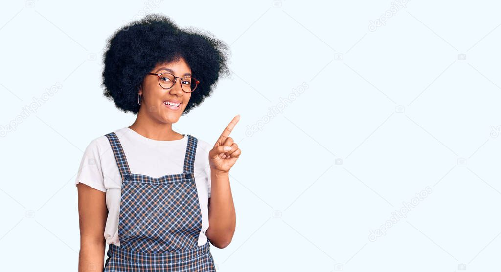 Young african american girl wearing casual clothes showing and pointing up with finger number one while smiling confident and happy. 