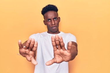 Gündelik kıyafetler giyen genç Afro-Amerikan adam avuç içi hareketlerini durduruyor, kızgın ve hayal kırıklığı ifadesi takınıyor. 
