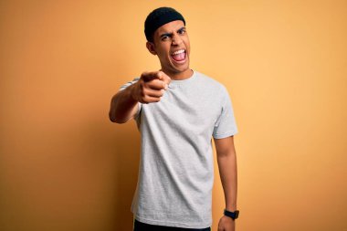 Yakışıklı Afro-Amerikan sporcusu sarı arka plan üzerine spor giysisi giyiyor. Kameraya kızgın ve sinirli olduğunu gösteriyor.