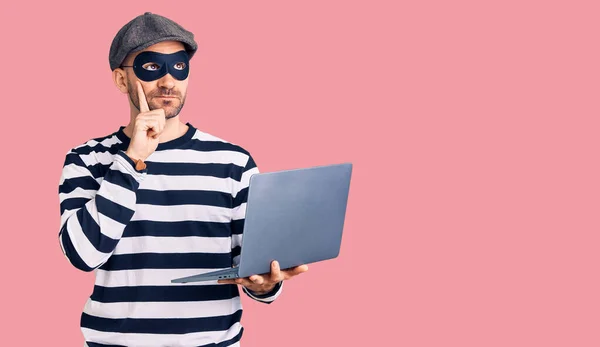 Young Handsome Man Wearing Burglar Mask Using Laptop Serious Face — Stock Photo, Image