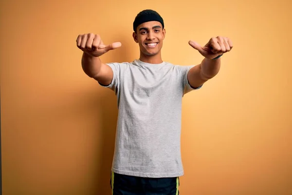 英俊的非洲裔美国运动员穿着黄色背景的运动服做运动 肯定用手做积极的手势 微笑着竖起大拇指 为成功感到高兴 赢的手势 — 图库照片