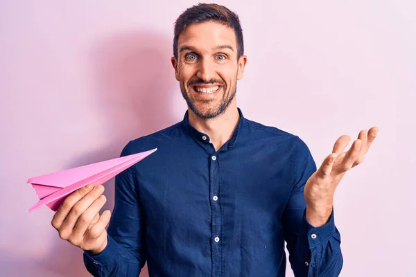 Jovem Homem Bonito Segurando Avião Papel Rosa Sobre Backgrournd Isolado — Fotografia de Stock