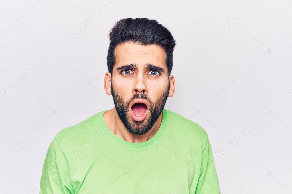 Young handsome man with beard wearing casual t-shirt scared and amazed with open mouth for surprise, disbelief face 