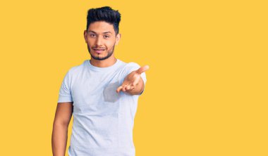 Yakışıklı Latin Amerikalı, sıradan kıyafetler giyen, gülümseyerek dostça tokalaşan, hoş geldin diyen genç adam. başarılı iş. 