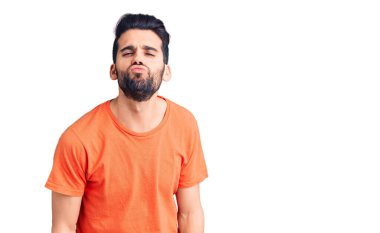 Sakallı, sıradan tişörtlü, kameraya bakıp havada öpücük yollayan yakışıklı genç bir adam. Güzel ve seksi. aşk ifadesi. 