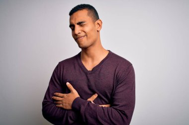 Beyaz arka plan üzerine gündelik kazak giyen genç ve yakışıklı Afro-Amerikan bir adam midesi üzerinde çünkü hazımsızlık, acı verici bir hastalık, kendini iyi hissetmiyor. Ache kavramı.