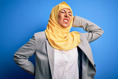 Orta yaşlı esmer iş kadını. Mavi arka plan üzerine geleneksel başörtüsü takıyor. Boyun ağrısı çekiyor.