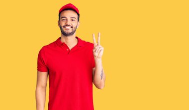 Genç, yakışıklı, kurye üniforması giyen, gülümseyen, kameraya göz kırpan ve zafer işareti yapan bir İspanyol. İki numara.. 