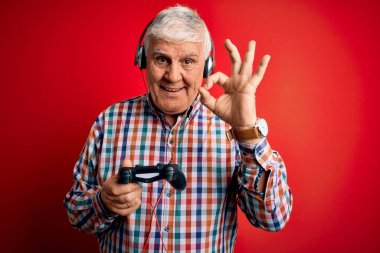 Kıdemli yakışıklı beyaz oyuncu oyun oynuyor joystick ve kulaklıkla tamam işareti yapıyor, mükemmel bir sembol