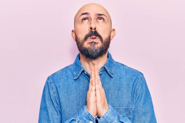 Gündelik giysiler giymiş genç yakışıklı bir adam elleri bağlı yalvarıyor ve dua ediyor. Yüzünde umut ifadesi var. Duygusal ve endişeli. Yalvarıyor. 
