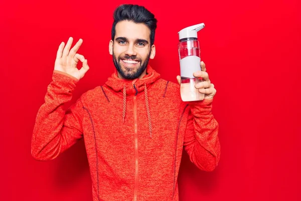 Joven Hombre Guapo Con Barba Usando Ropa Deportiva Bebiendo Botella — Foto de Stock