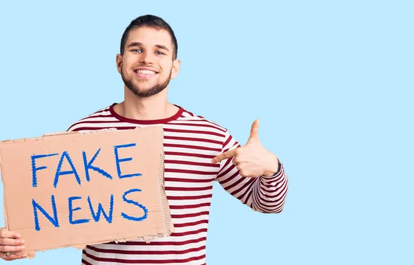 Joven Hombre Guapo Sosteniendo Banner Mensaje Noticias Falsas Señalando Con — Foto de Stock