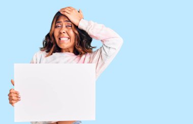 Genç, güzel, melez bir kadın elinde boş yeri olan karton bir afiş tutuyor. Eli boş, şaşırmış ve sinirli bir yüzü var. 