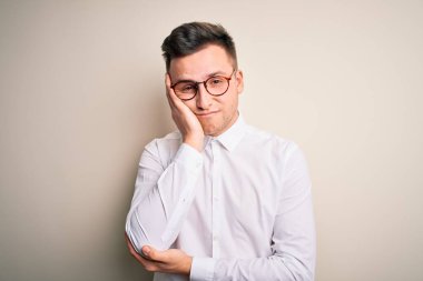 Genç yakışıklı iş adamları gözlük takıyor ve zarif gömlekler giyip izole edilmiş arka planda yorgun ve bunalımlı görünerek kollarını kavuşturuyor..