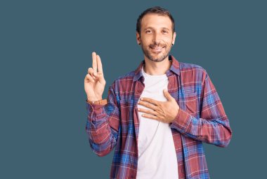 Genç, yakışıklı, sıradan kıyafetler giyen, gülümseyen, elleri göğsünde ve parmakları havada küfür eden, sadakat yemini eden bir adam. 