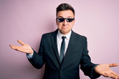 Genç, beyaz, beyaz, komik, cani gözlüklü, kafası karışık, elleri ve kolları havada bir iş adamı. Şüphe kavramı.