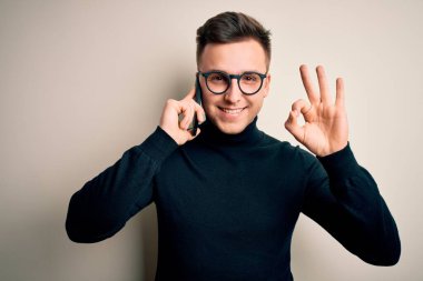 Yakışıklı beyaz bir adam akıllı telefondan konuşuyor. Parmaklarıyla imza atıyor. Mükemmel bir sembol.