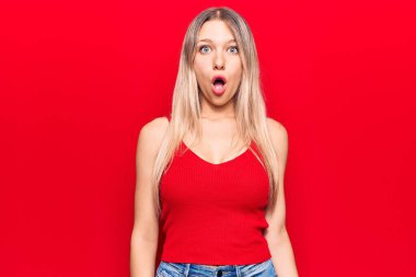 Gündelik kıyafetler giyen genç sarışın kadın şaşkınlık, korku ve şaşkınlık dolu bir ifade içinde.. 