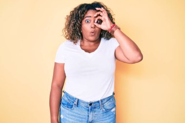 Genç Afro-Amerikan artı iri yarı kadın normal beyaz tişört giyiyor. Şaşırmış yüz ifadesiyle şok olmuş, parmaklarından bakan gözler. İnançsız ifade. 