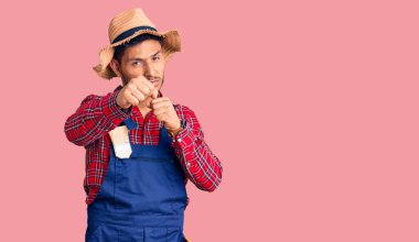 Yakışıklı Latin Amerikalı genç adam. Tamirci üniforması giyiyor. Yumruk yumruğa dövüşüyor. 