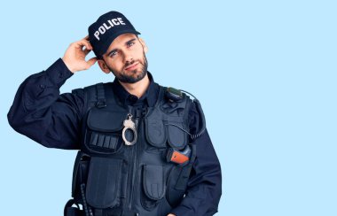 Polis üniforması giyen sakallı yakışıklı genç adam soru sorup şaşırıyor. Şüpheyle kararsız, kafa kafaya düşünerek. Düşünceli kavram. 