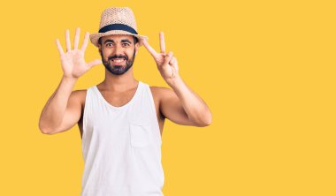 Gündelik yaz şapkası takan genç İspanyol adam yedi numarayı gösterip işaret ederken kendine güvenen ve mutlu bir şekilde gülümsüyor.. 