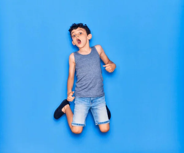 愛らしい子供を身に着けてカジュアル服ジャンプ上の隔離された青の背景 — ストック写真