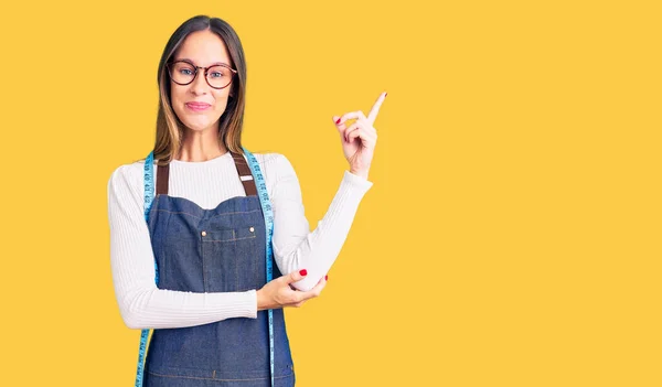 Hermosa Morena Mujer Joven Modista Diseñador Usando Delantal Atelier Sonriendo —  Fotos de Stock