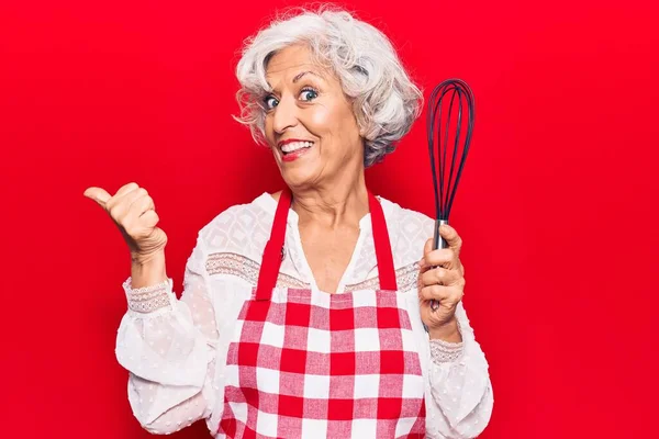 Senior Grey Haired Woman Wearing Apron Holding Whisk Pointing Thumb — Stock Photo, Image