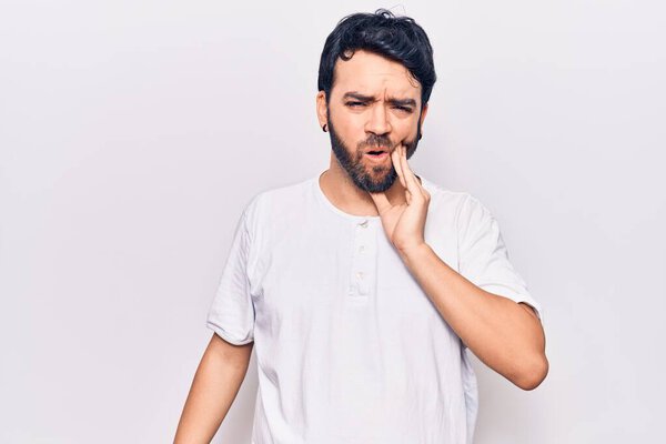 Young hispanic man wearing casual clothes touching mouth with hand with painful expression because of toothache or dental illness on teeth. dentist 