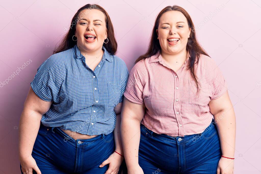 Young plus size twins wearing casual clothes winking looking at the camera with sexy expression, cheerful and happy face. 