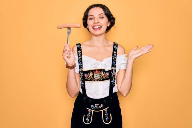 Mavi gözlü genç Alman kadın elinde çatalla sosis tutuyor. Çok mutlu ve heyecanlı. Kazanan ifade zaferi kutluyor.