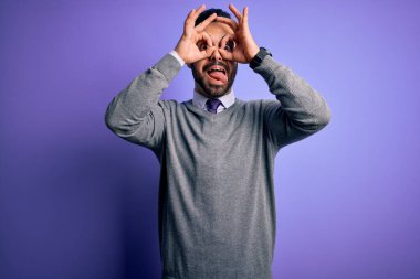 Mor arka planda sıradan bir kravat takan yakışıklı bir iş adamı. Dürbün gibi güzel hareketler yapıyor. Gözleri parmaklarından bakıyor. Çılgın ifade.