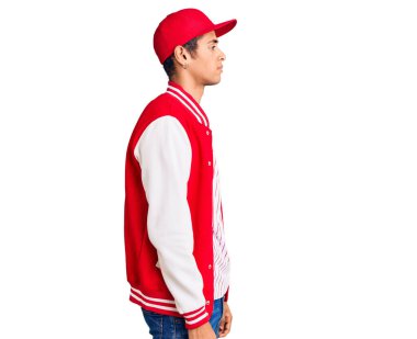 Beyzbol üniforması giyen genç Afro-Amerikan bir adam kendine güvenen bir gülümseme ile profilini rahatlatmak için poz veriyor.. 