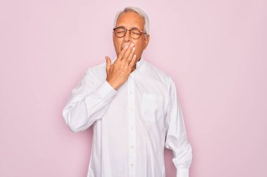 Middle age senior grey-haired man wearing glasses and business shirt over pink background bored yawning tired covering mouth with hand. Restless and sleepiness. clipart