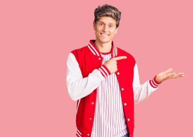 Beyzbol üniforması giyen yakışıklı genç adam kameraya hayret ediyor ve gülümsüyor.. 