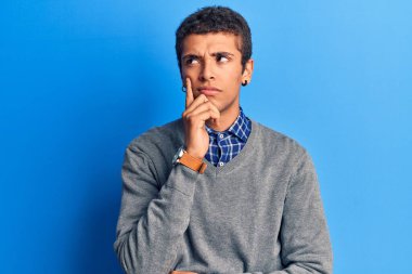 Genç Afrikalı Amerikalı sıradan kıyafetler giyen ciddi yüzlü eli çenesinde soru soran, kafa karıştırıcı fikirleri düşünceli genç bir adam. 